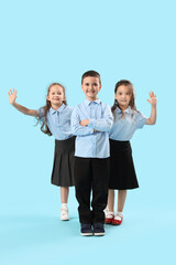 Little schoolchildren on light blue background