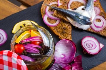 Pickled anchovies in homemade marinade of olive oil, vinegar, lemon, sea salt with spices and purple onion served with rye bread..