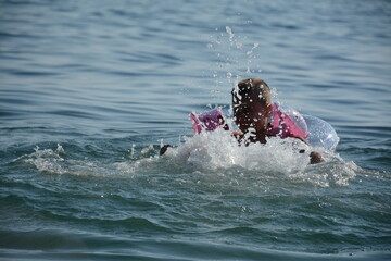 A child in a circle and armlets swims in the warm sea