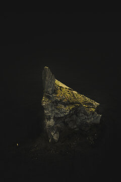 Aerial view of a big rock on a black sand beach in Vik, Iceland.