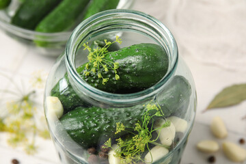 Jar with fresh cucumbers for preservation on white tile background