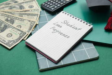 Notepad with text STUDENT LOAN FORGIVENESS, dollar banknotes and calculator on green background