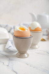 Holders with boiled chicken eggs on white background