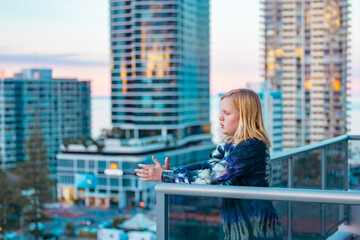 Fototapeta na wymiar Boy standing on balcony admiring the view from a highrise apartment in Surfers Paradise on the Gold Coast, Queensland Australia