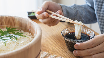 木桶に入った和食の素麺・そうめんを食べる男性