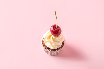 Tasty cherry cupcake on pink background