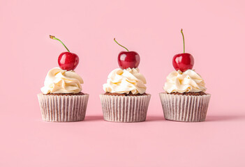 Tasty cherry cupcakes on pink background