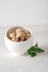 Bowl with canned mushrooms on light background