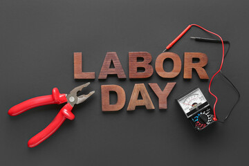 Composition with pliers, multimeter and text LABOR DAY on black background