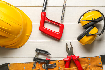 Composition with different tools, hardhat and ear muffs on white wooden background. Labor Day...
