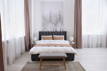 Comfortable bed and lamps on bedside tables in light spacious room. Stylish interior