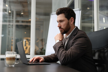 Man working on laptop at black desk in office