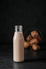 Bottle of tasty potato milk on black background