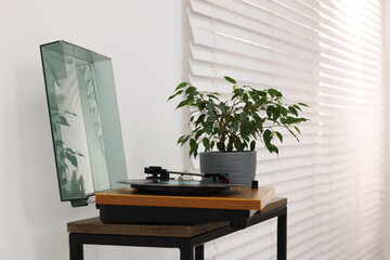 Record player and houseplant on wooden table at home