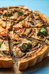 Delicious quiche with mushrooms on light blue table, closeup