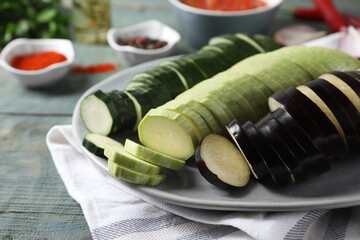 Cooking delicious ratatouille. Plate with fresh cut vegetables on light blue wooden table, closeup