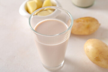 Glass of tasty potato milk on light background