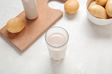 Glass of tasty potato milk on light background