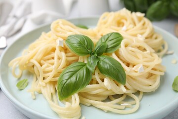 Delicious pasta with brie cheese and basil leaves on table, closeup