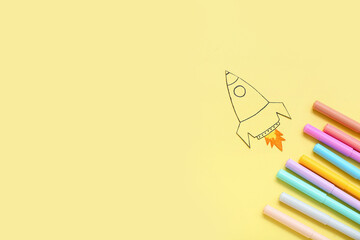 Drawn rocket and markers on yellow background