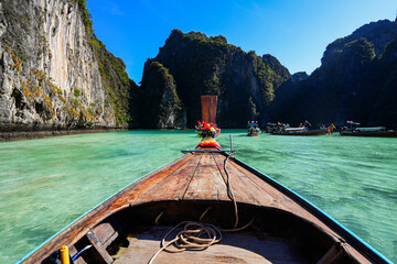 Bow of a long tail boat entering Pi Leh lagoon, surrounded by karstic limestone cliffs, on Koh Phi...