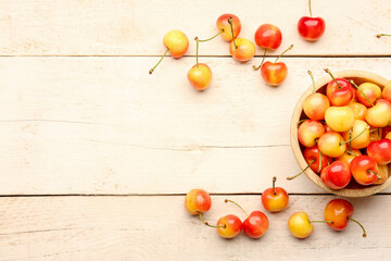 Bowl with sweet yellow cherries on white wooden background