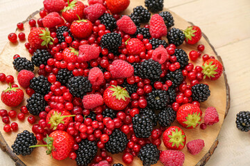 Board with fresh berries on light wooden background, closeup