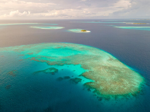 Aerial view of tropical island at sunrise near the Baa Atoll, Maldives.