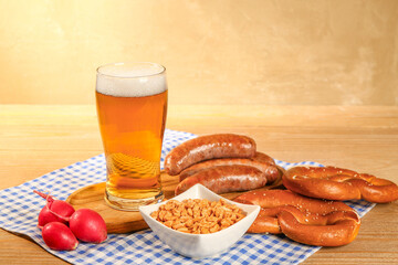 Glass of cold beer and different snacks on wooden background. Oktoberfest celebration