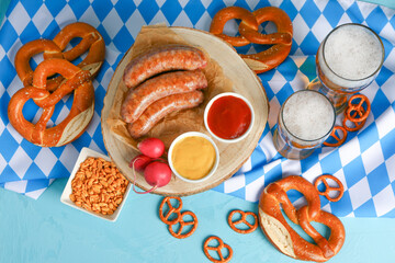 Glasses of cold beer and different snacks on blue background. Oktoberfest celebration