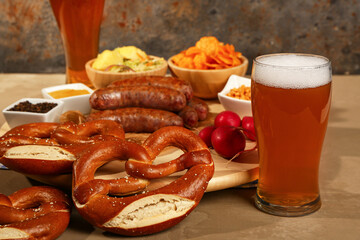 Glass of cold beer and different snacks on brown background. Oktoberfest celebration