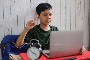 Asian child looking at laptop computer and raise hand for video call study online or online...