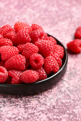Tray with fresh raspberries on purple background