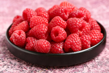 Tray with fresh raspberries on purple background