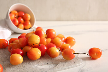 Board and cup with sweet yellow cherries on white background