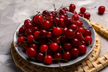 Plate with red sweet cherries on grunge background