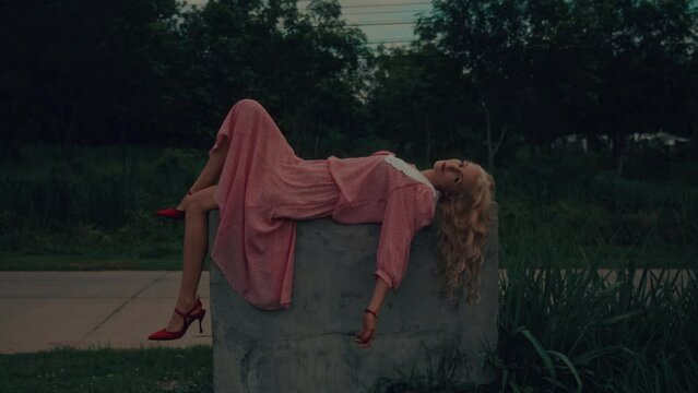 A woman in a vintage dress lying on the concrete cube