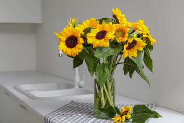 Vase with beautiful sunflowers on white kitchen counter