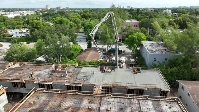 Aerial view of pouring fresh concrete into building foundation over reinforcing steel bars with help of pump truck. Construction of commercial premises in big city