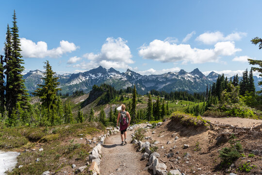 Woman hiking on trail through beautiful majestic mountains landscape in the stunning Mt. Rainier National Park, Pacific Northwest, Washington State