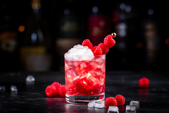 Rosso berry crush alcoholic cocktail drink with red vermouth, raspberries, currants and ice, dark bar counter background, copy space