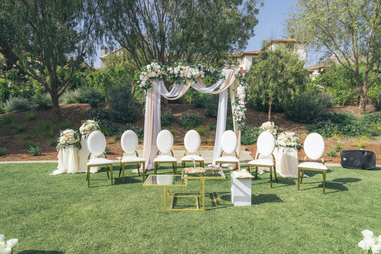 Outdoor Wedding Ceremony Setup with Floral Arch, White Chairs, Draped Fabric, and Fresh Flowers &ndash; Muslim Wedding, Marriage Celebration, Love, Romance, Commitment, Engagement, Elegant Venue, Islamic Cu