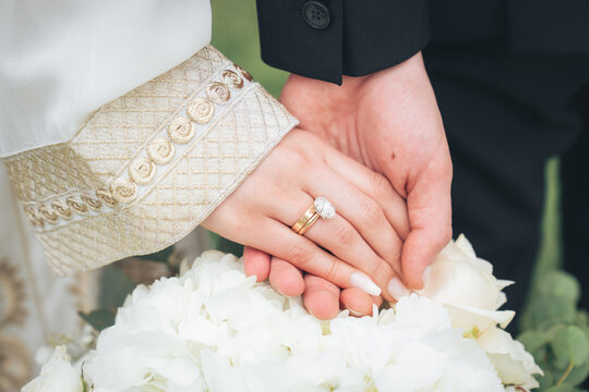 Close Up of Bride and Groom Holding Hands with Wedding Rings and White Flowers &ndash; Muslim Wedding, Marriage Ceremony, Love, Romance, Commitment, Engagement, Bridal Jewelry, Islamic Culture, Marriage