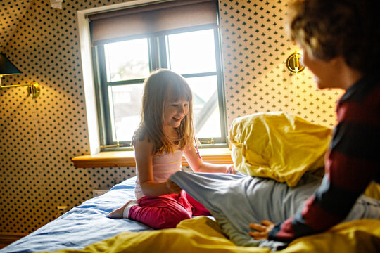 Young boy and girl having a pillow fight in the bedroom