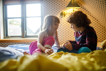 Young boy and girl using a digital tablet in the bedroom together