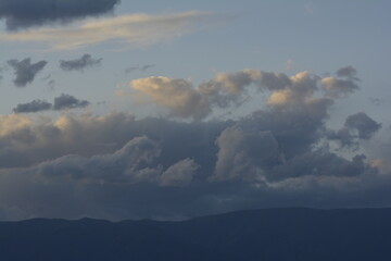 cielo con nubes blancas y grises y montañas al atardecer