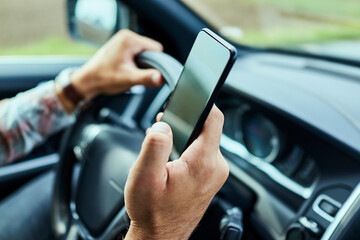 Man using a smart phone while driving a car in the city