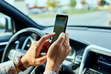 Man using a smart phone while driving a car in the city