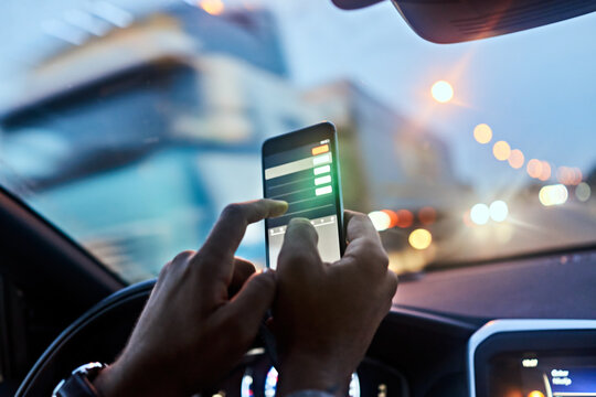 Man using a smart phone while driving a car on the road