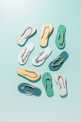 Female summer shoes sandals as creative minimal pattern with hard shadow, blue green yellow flip flops on turquoise gradient color background. Aesthetic trend summer fashion concept, life style